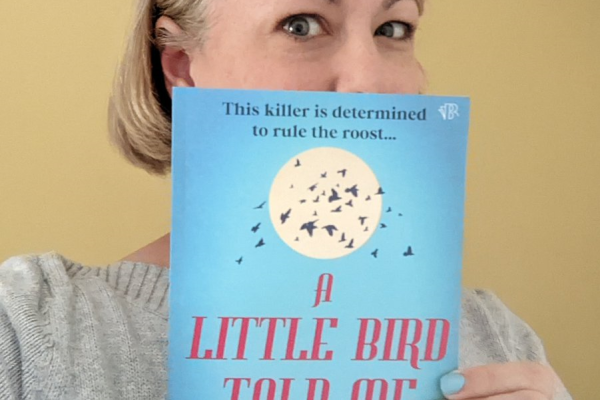Image of Dr Rachael Gray holding her debut novel A Little Bird Told Me