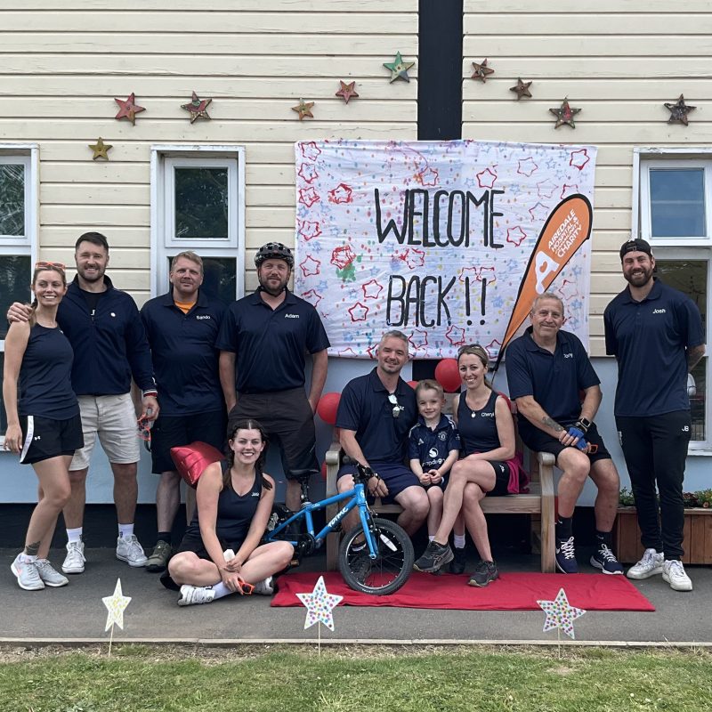 Image of The Long Way Home cycling team under a banner that read welcome back